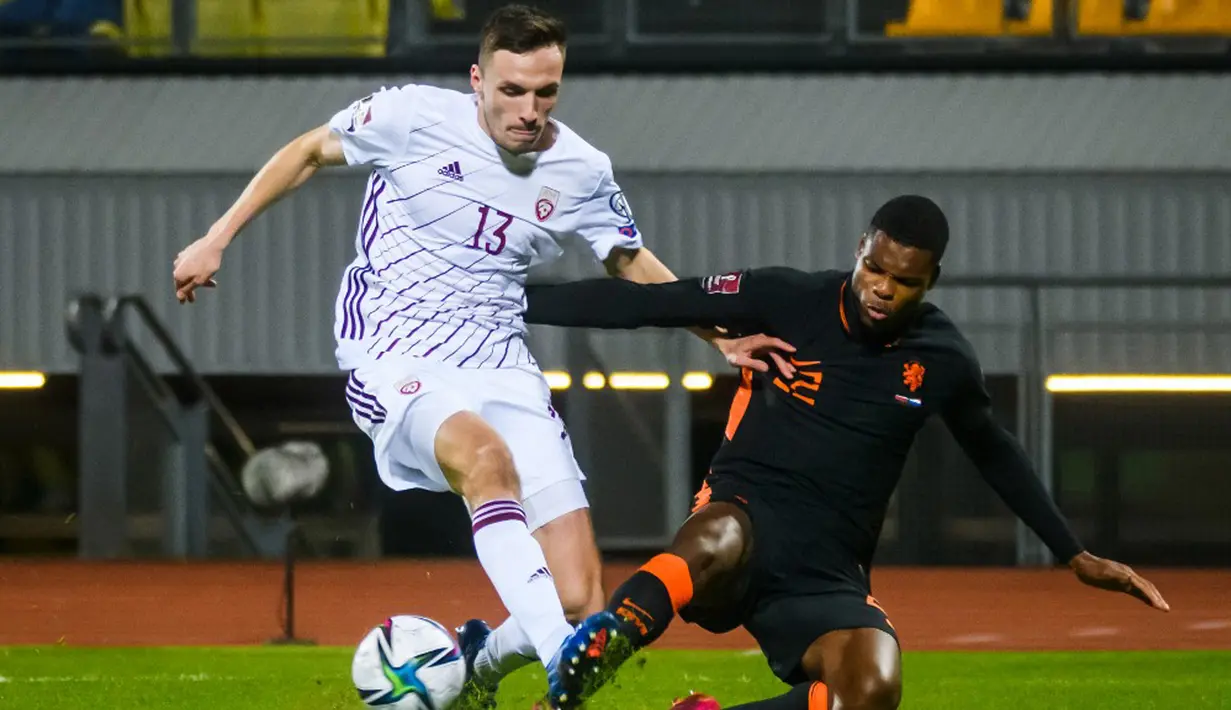 Pemain Latvia Raivis Andris Jurkovskis (kiri) berebut bola dengan pemain Belanda Denzel Dumfries pada pertandingan sepak bola kualifikasi Grup G Piala Dunia 2022 di Stadion Daugava, Riga, Latvia, 8 Oktober 2021. Belanda menang 1-0. (Gint Ivuskans/AFP)