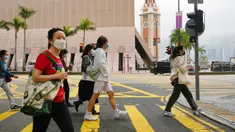 Orang-orang yang memakai masker berjalan di sepanjang jalan di Hong Kong, Jumat (28/1/2022). Hong Kong memangkas masa karantina wajib bagi orang-orang yang datang dari luar negeri dari 21 menjadi 14 hari. (AP Photo/Kin Cheung)
