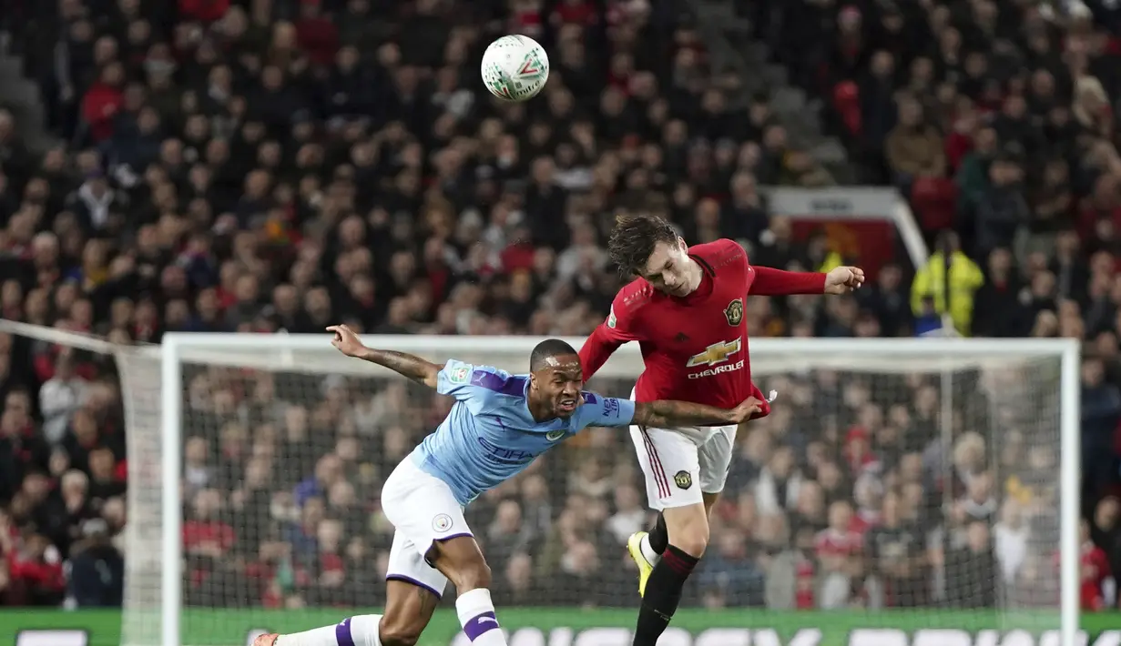 Penyerang Manchester City, Raheem Sterling berebut bola udara dengan bek Manchester United, Victor Lindelof pada pertandingan leg pertama semifinal Piala Liga Inggris di Old Trafford (7/1/2020). City menang 3-1 atas MU. (AP Photo / Jon Super)
