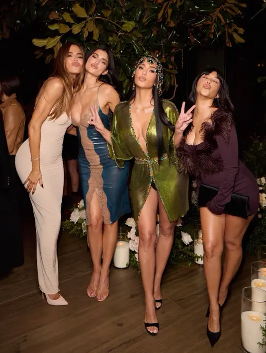 Bersama tiga tamu lain, Kim berpose ceria dengan gaun hijau metaliknya. Di sebelahnya, tampil gaun slip panjang krem berbahan rajut bertekstur, gaun satin biru dengan panel renda warna nude dan heels transparan, serta mini dress ungu plum berhias bulu di bagian dada dengan clutch satin hitam. [@kimkardashian]