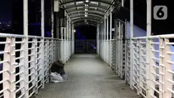 Pemulung beristirahat di Jembatan Penyebrangan Orang (JPO) Jalan Rasuna Said, Jakarta, Selasa (7/4/2020). Pemerintah telah resmi menetapkan Pembatasan Sosial Berskala Besar (PSBB) di wilayah DKI Jakarta dalam rangka percepatan penanganan COVID-19. (Liputan6.com/Helmi Fithriansyah)