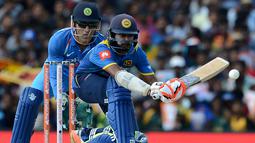 Pemain kriket Sri Lanka Niroshan Dickwella (kana) diawasi oleh wicketkeeper India Mahendra Singh Dhoni burusaha memukul bola dalam pertandingan kriket One Day International (ODI) di Dambulla (20/8). (AFP Photo/Lakruwan Wanniarachchi)