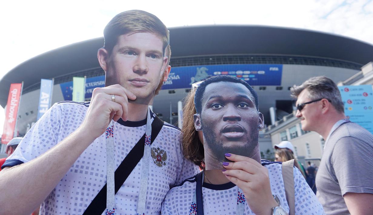 Suporter menggunakan topeng berwajah Kevin de Bruyne dan Romelu Lukaku di Stadion Saint Petersburg, Rusia. (Bola.com/Okie Prabhowo)