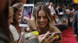 Aktris Margot Robbie berselfie dengan penggemar saat tiba menghadiri pemutaran perdana film 'Once Upon A Time in Hollywood' di Berlin, Jerman (1/8/2019). Margot Robbie tampil cantik mengenakan gaun hijau zaitun dari koleksi Jacquemus's Spring 2020. (AFP Photo/Odd Andersen)