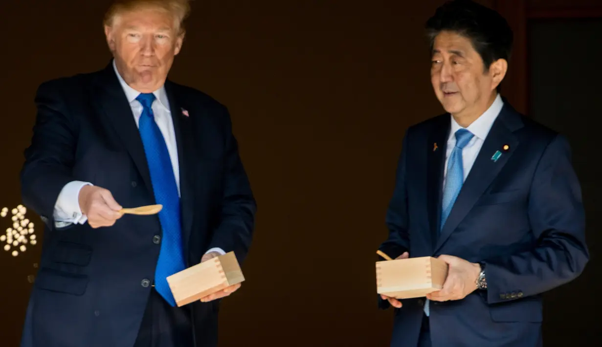 Presiden AS Donald Trump dan PM Jepang Shinzo Abe memberi makan ikan di kolam koi Istana Akasaka, Tokyo, Senin (6/11). Beragam momen terlihat dalam kunjungan Presiden Donald Trump ke Jepang. (AP/Andrew Harnik)