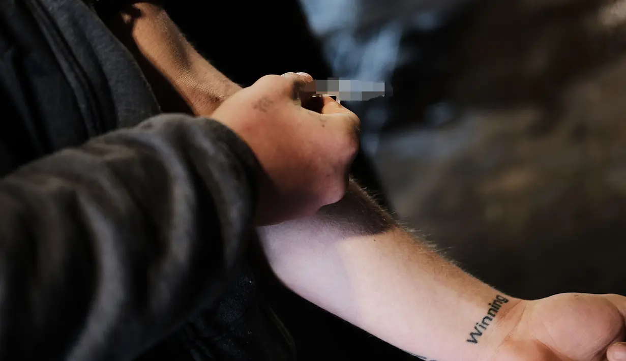 Seorang pria menyuntikkan heroin di lenganya di kawasan yang menjadi pusat penggunaan heroin di Kensington, Philadelphia (24/1). DEA Amerika Serikat juga menjelaskan jumlah korban jiwa tahun ini diperkirakan makin menambah.(Spencer Platt/Getty Images/AFP)