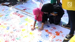 Mahasiswa jurusan Kriminologi Fisip UI mendampingi anak-anak bermain cap tangan saat gelaran Car Free Day di kawasan Bundaran HI, Jakarta, Minggu (18/11). Permainan ini bertujuan mengurangi anak-anak bermain gawai. (Liputan6.com/Helmi Fithriansyah)
