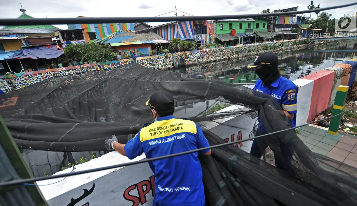 Petugas Dinas Sumber Daya Air Aliran Timur melepas kain waring atau jaring yang menutupi Kali Item di Kemayoran, Jakarta, Rabu (14/11). Pelepasan waring juga untuk mempermudah dalam membersihkan sampah di aliran Kali Item. (Merdeka.com/Iqbal S. Nugroho)