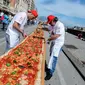 Sejumlah koki ahli berupaya mencetak rekor dunia dengan membuat pizza terpanjang di dunia, di sepanjang pinggir Laut Naples, Italia, 18 Mei 2016. Pizza itu memiliki ukuran sekitar 1 mil dan terbentang di sepanjang pinggir Laut Naples. (Mario LAPORTA/AFP)