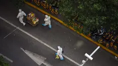 Petugas kesehatan yang mengenakan alat pelindung diri berjalan di jalan saat lockdown tahap kedua akibat COVID-19 di Distrik Jing'an, Shanghai, China, Rabu (6/4/2022). (Hector RETAMAL/AFP)