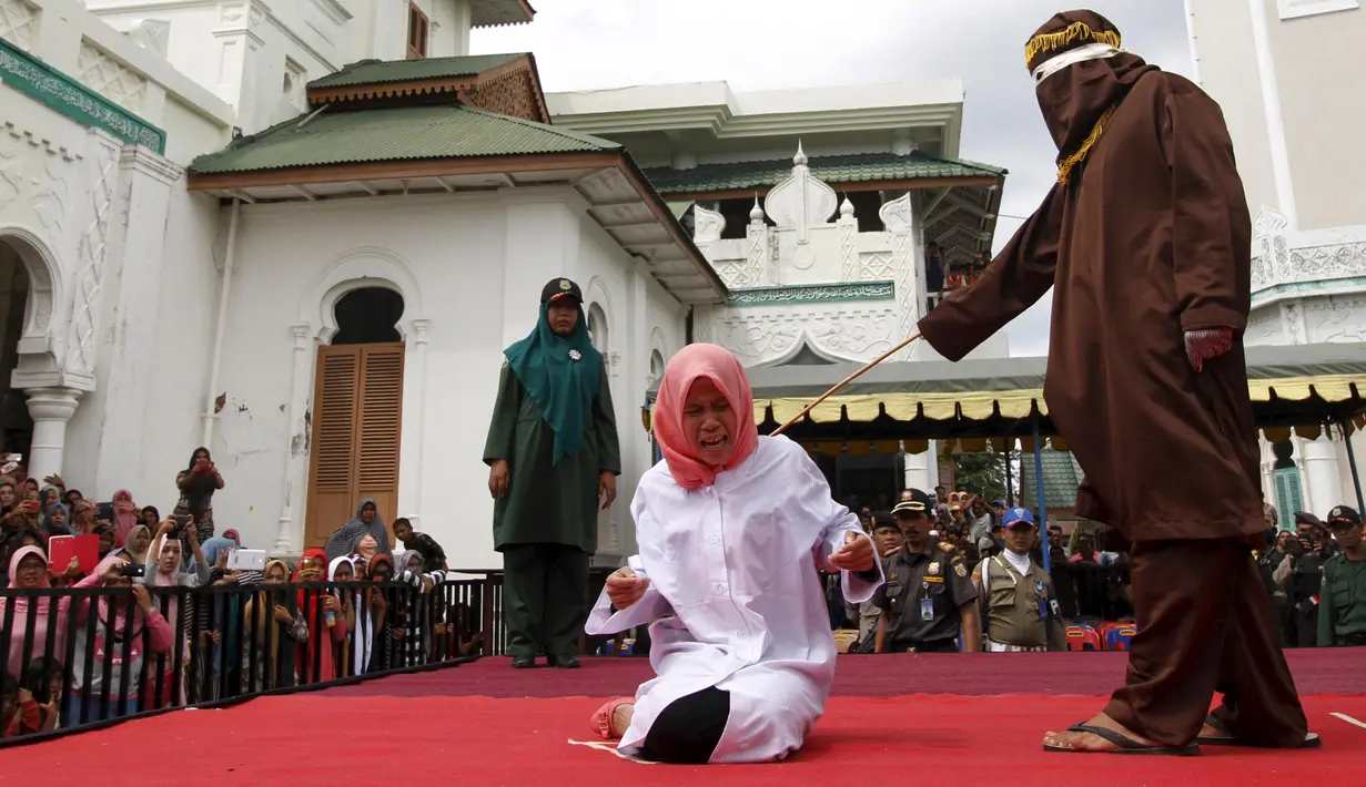 Nur Elita tampak meringis kesakitan saat petugas menyabetkan rotan ke punggungnya di halaman Masjid Baiturrahim, Ulee Lheue, Banda Aceh, Senin (28/12). Nur yang merupakan terpidana kasus khalwat mendapat 5 kali cambukan (REUTERS/Junaidi Hanafiah)