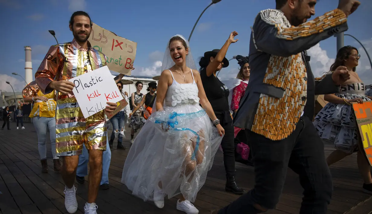 Aktivis lingkungan berpakaian sampah kebanyakan dari plastik dalam unjuk rasa yang disebut Revolusi Mode di Tel Aviv, Israel, 19 November 2021. Aksi ini dilakukan untuk meningkatkan kesadaran iklim. (AP Photo/Oded Balilty)