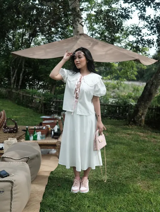 Pada salah satu kesempatan, Rachel tampil memikat dengan gaya coquette yang feminin. Ia memadukan puffer blouse with collar dan rok midi serba putih. Penampilannya dipermanis dengan sepatu dan mini bag nuansa baby pink. [@rachelvennya].