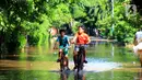 Dua anak sedang bermain sepeda melintasi banjir di kawasan Jalan Raya Kayu Putih, Jakarta, Minggu (23/2/2020). Usai hujan deras sejak Sabtu (22/2) malam hingga dini hari menyebabkan banjir di Jalan Raya Kayu Putih, Jakarta, Minggu (23/2). (merdeka.com/Magang/Muhammad Fayyadh)