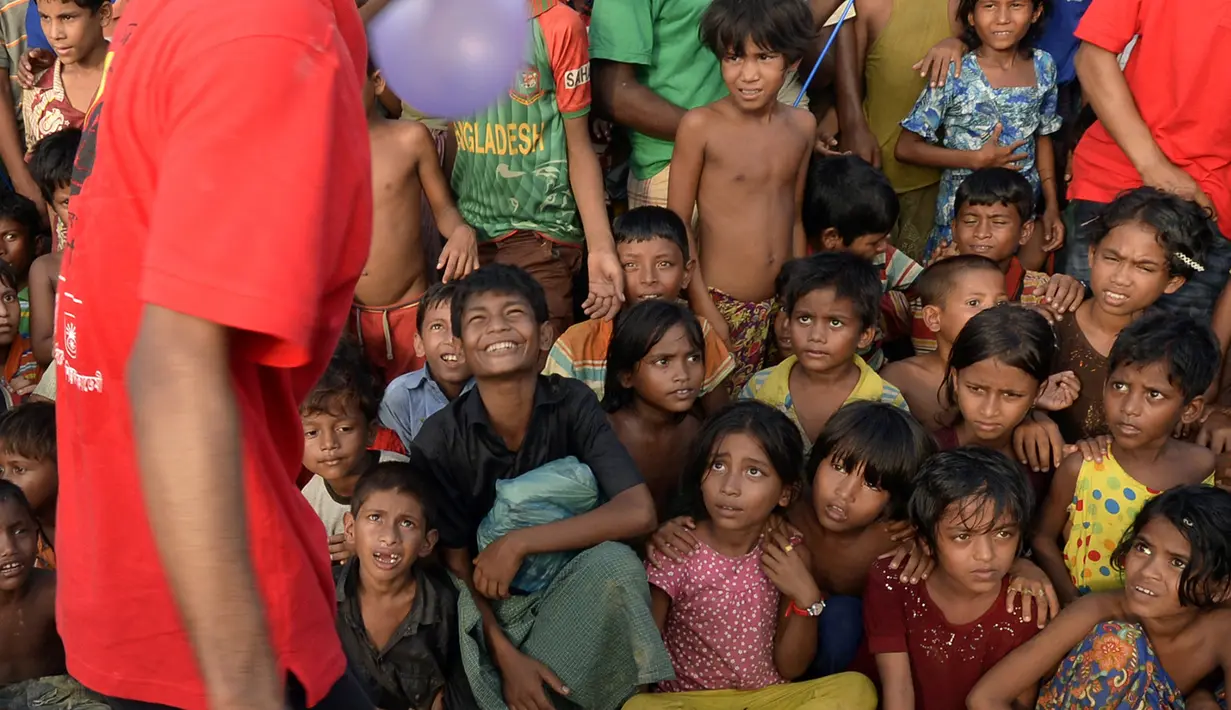 Kelompok teater Drama Therapy mengenakan kostum badut menghibur anak-anak pengungsian Rohingya di kamp pengungsi Kutupalong, Bangladesh (28/10). (AFP Photo/Tauseef Mustafa)