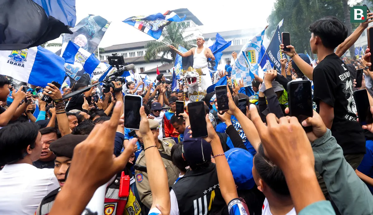 Gubernur Jawa Barat, Dedi Mulyadi, mengibarkan bendera saat merayakan Persib Bandung juara BRI Liga 1 di Gedung Sate, Bandung, Jawa Barat, Minggu, (25/5/2025). (Bola.com/M Iqbal Ichsan)
