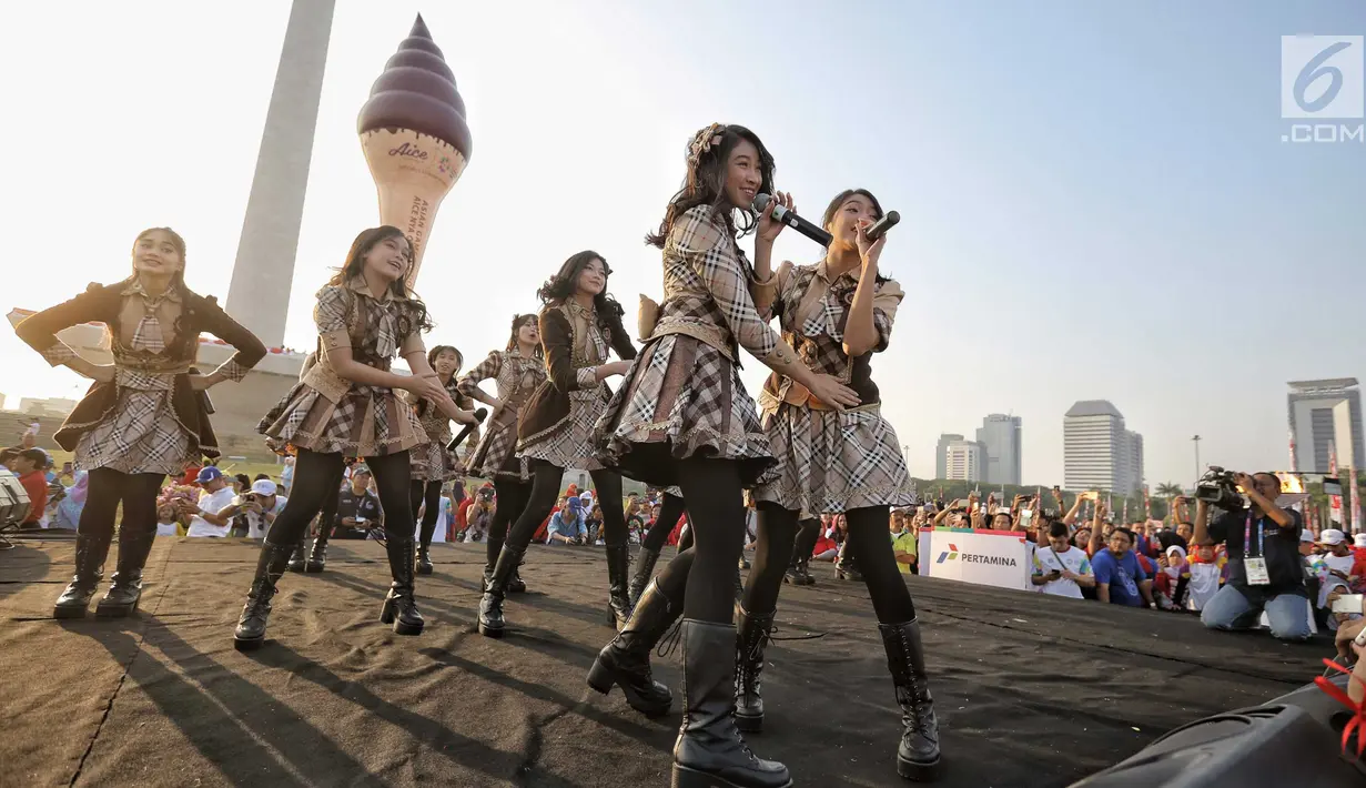 Aksi para personel girlband JKT48 saat tampil dalam puncak Kirab Obor Asian Games 2018 di Monas, Jakarta, Sabtu (18/8). Obor Asian Games 2018 diarak dari Monumen Nasional (Monas) menuju Stadion Utama Gelora Bung Karno (SUGBK). (Liputan6.com/Faizal Fanani)