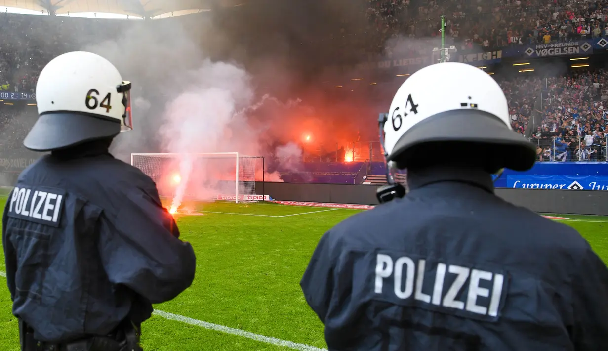 Petugas kepolisian berusaha menenangkan suporter yang mengamuk saat pertandingan antara Hamburg SV melawan VfL Borussia Moenchengladbach di Volksparkstadion, Sabtu (12/5/2018). Hamburg SV terdegradasi dari Bundesliga Jerman. (AP/Michael Sohn)