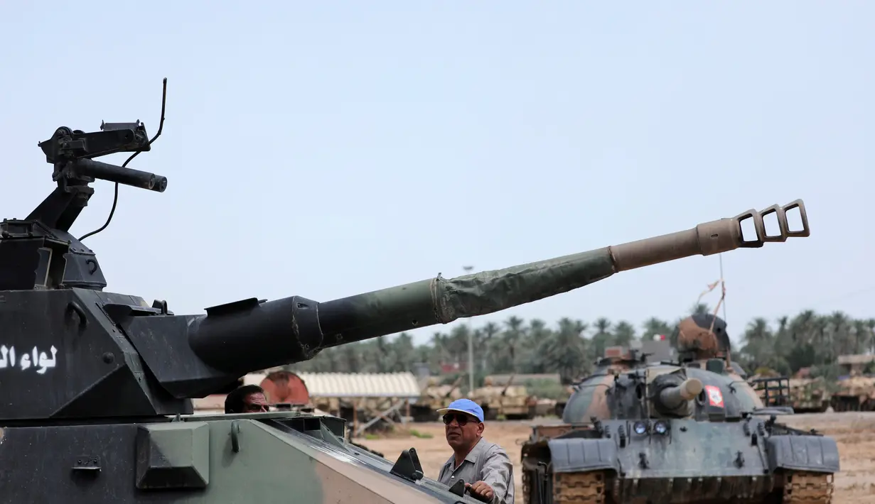 Seorang teknisi militer Pasukan Mobilisasi Populer Irak (Hashid Shaabi) mengecek tank yang rusak di sebuah bengkel di Kerbala, Irak (7/5). Bengkel ini menjadi salah satu lokasi perbaikan kendaraan-kendaraan militer rusak usai dipergunakan untuk perang. (Reuters/Abdullah Dhiaa Al- Dien)