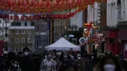 Wanita berjalan melalui Chinatown di Soho di London, Selasa (28/12/2021). Padahal banyak negara Eropa telah memulai pembatasan lebih lanjut pada populasi mereka karena jumlah kasus COVID-19 terkait Omicron meningkat, dan mereka bertujuan untuk menahan penyebaran virus. (AP Photo/Alastair Grant)