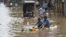 Dua orang anak bermain saat banjir melanda kawasan mereka di Gauhati, India, Rabu (14/6). Angin monsun yang mendatangi India berdampak pada tingginya curah hujan yang menyebabkan banjir. (AP Photo / Anupam Nath)