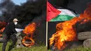 Demonstran membakar ban saat protes terhadap serangan militer Israel ke Kota Nablus, Tepi Barat, di sepanjang pagar perbatasan dengan Israel di sebelah timur Kota Gaza, 22 Februari 2023. Para pejabat Palestina mengatakan sejumlah warga Palestina telah terbunuh dan lebih dari seratus orang terluka dalam serangan tentara Israel yang jarang terjadi di Tepi Barat. (AP Photo/Adel Hana)
