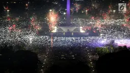 Ribuan warga mengabadikan moment kembang api pada malam pergantian tahun baru 2018 di kawasan silang Monumen Nasional (Monas), Jakarta, Senin (1/1/2018). Monas menjadi salah satu lokasi pilihan warga saat malam tahun baru. (Liputan6.com/Johan Tallo)