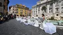 Pengantin perempuan yang mengenakan gaun pernikahan mereka melakukan flashmob saat aksi protes di Trevi Fountain, Roma, Selasa (7/7/2020). Mereka memprotes kebijakan pemerintah Italia yang masih melarang adanya acara pernikahan, meski penerapan lockdown sudah dilonggarkan. (Tiziana FABI/AFP)