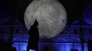 Seorang pria melewati pertunjukan cahaya malam di Lyon, Prancis tengah, Rabu (8/12/2021). Jutaan orang diperkirakan akan menghadiri acara Festival of Lights selama empat hari di kota itu. (AP Photo/Laurent Cipriani)