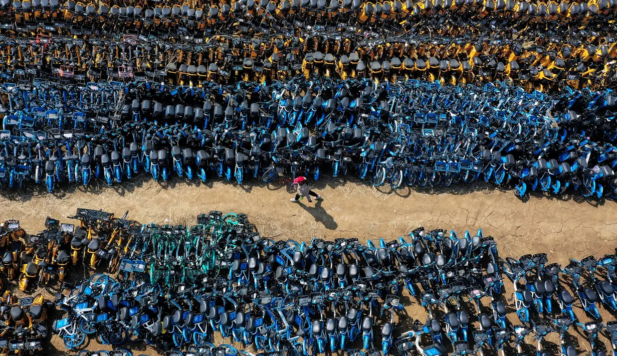 Penampakan dari udara tumpukkan sepeda publik yang ditinggalkan di Shenyang, timur laut China pada 19 April 2021. Ribuan sepeda yang awalnya disewakan secara online tersebut, dibiarkan terbengkalai karena banyak operator penyewaan sepeda yang bangkrut akibat pandemi Covid-19. (STR/AFP)