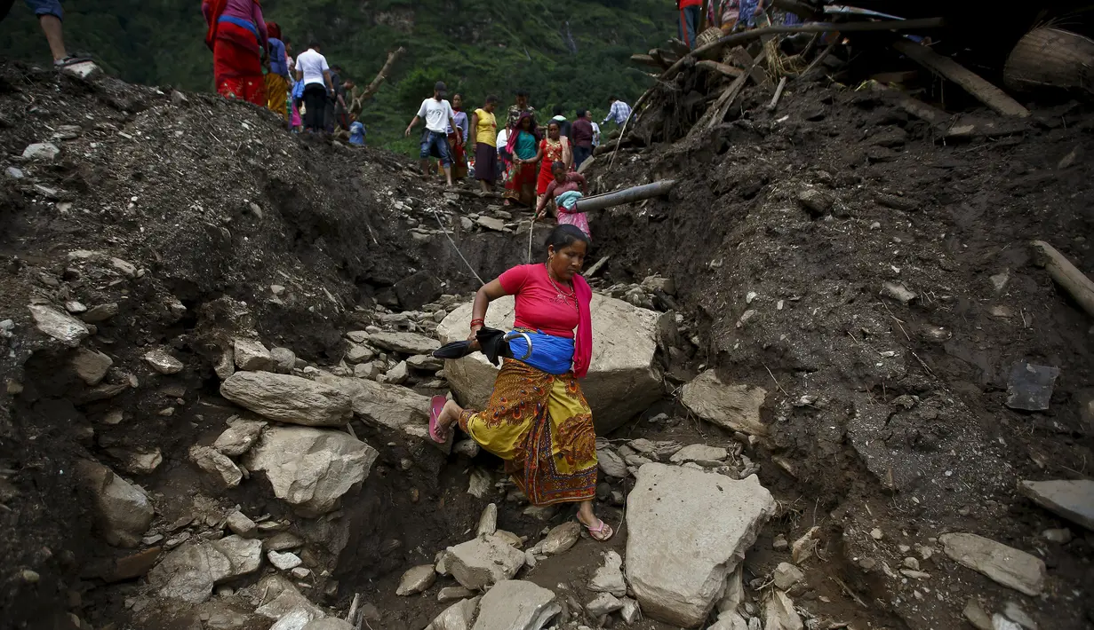 Seorang wanita berjalan di daerah yang terkena longsor di Desa Lumle, Nepal (30/7/2015). Tanah longsor yang dipicu hujan deras tersebut menewaskan sedikitnya 30 orang dan menghacurkan puluhan rumah. (REUTERS/Navesh Chitrakar)