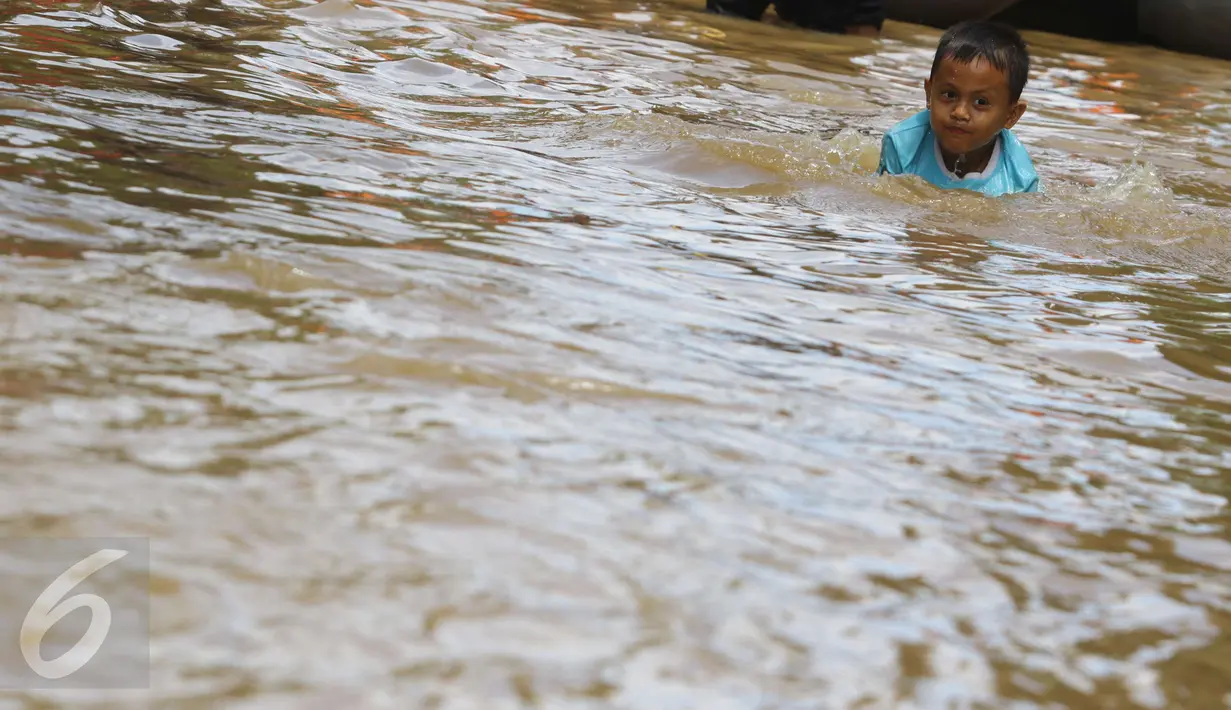 Seorang anak bermain di tengah jalan permukiman Bukit Duri, Jakarta yang terendam banjir, Kamis (16/2). Meluapnya Bendungan Katulampa, Bogor, menyebabkan permukiman kawasan Bukit Duri tergenang air dengan ketinggian 10 - 80 cm. (Liputan6.com/Helmi Afandi)
