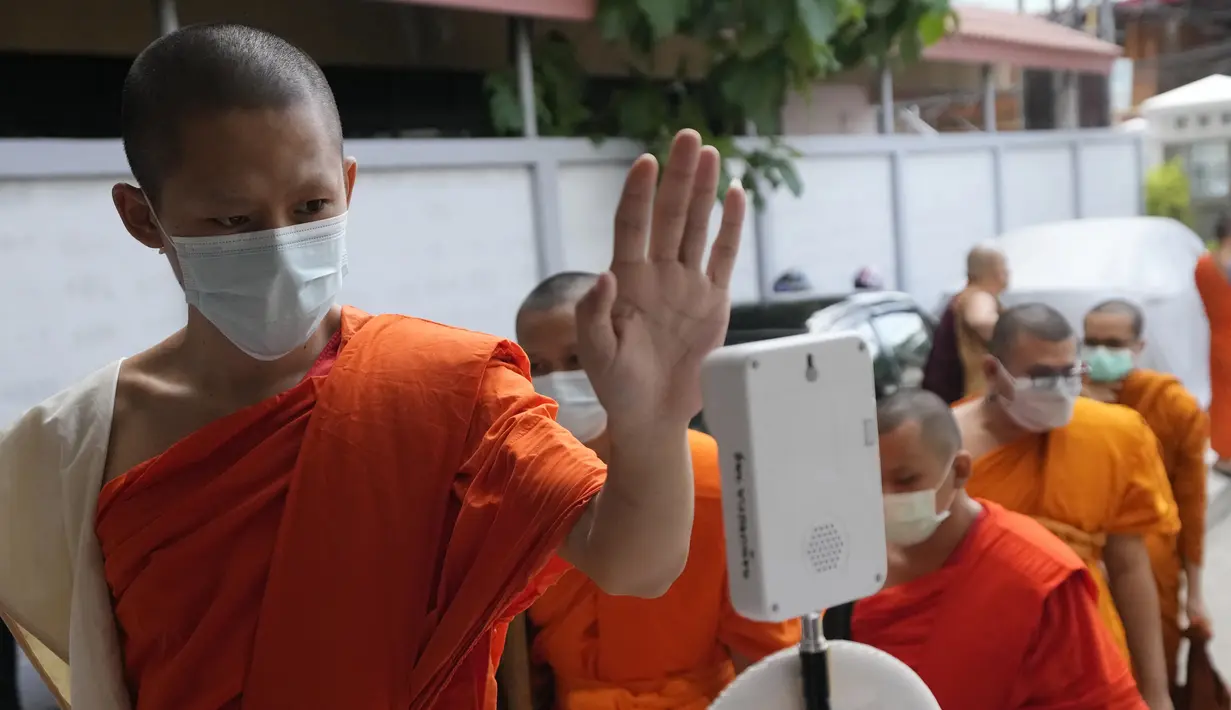 Seorang biksu memeriksa suhu tubuhnya sebelum menerima vaksin AstraZeneca COVID-19 di Wat Srisudaram di Bangkok, Thailand (30/7/2021). Thailand sedang berjuang untuk menahan wabah terbarunya yang dipicu oleh varian Delta yang sangat menular, dengan infeksi dan kematian yang meroket. (AP Photo/Sakcha
