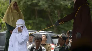 Tjia Nyuk Hwa dicambuk di luar Masjid Babussalam, Banda Aceh, Aceh, Indonesia, Selasa (27/2). Tjia Nyuk Hwa bersama suaminya, Dahlan Silitonga dicambuk karena bermain judi. (AFP FOTO/CHAIDEER MAHYUDDIN)