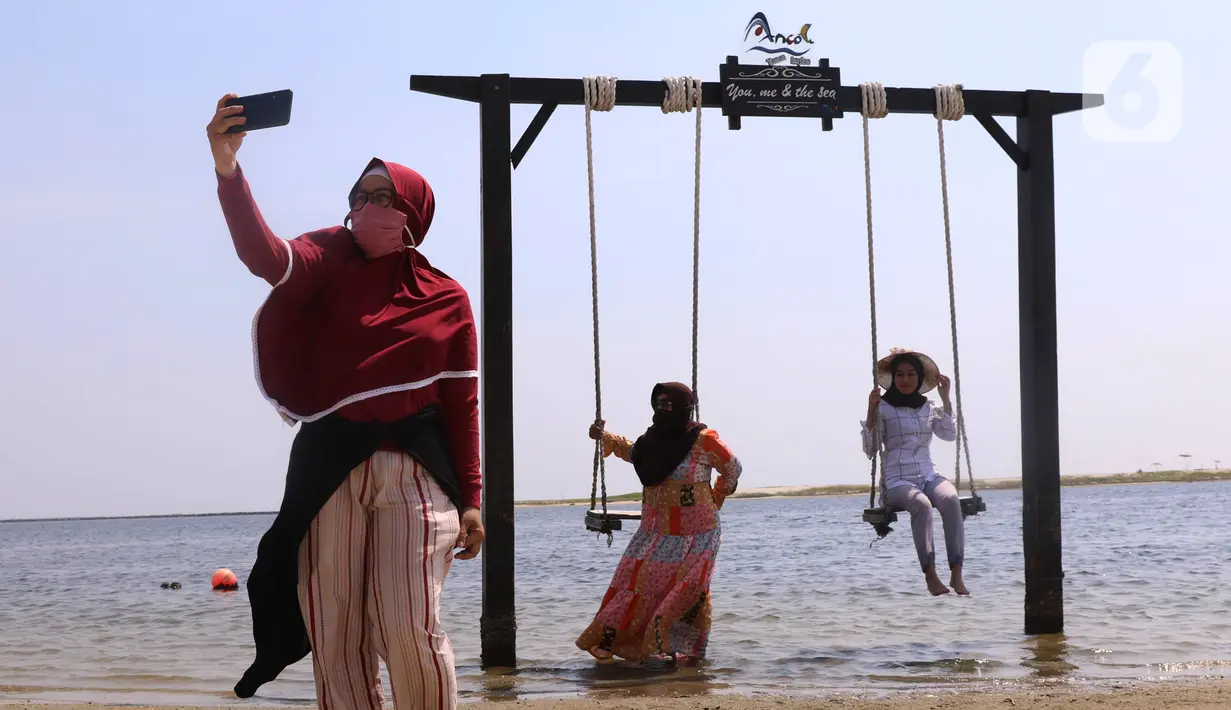 Pengunjung menikmati suasana Pantai Festival Taman Impian Jaya Ancol, Jakarta, Sabtu (20/6/2020). Setelah ditutup selama dua bulan akibat pandemi COVID-19, Kawasan rekreasi Taman Impian Jaya Ancol kembali dibuka. (Liputan6.com/Angga Yuniar)