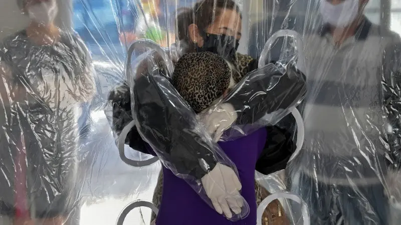 Suasana haru saat Elisabete Nagata memeluk adik iparnya yang berusia 76 tahun, Luiza Nagata, melalui tirai plastik transparan di suatu panti jompo di Sao Paulo, Brasil, pada 13 Juni 2020. (Photo Credit: AFP/ NELSON ALMEIDA)