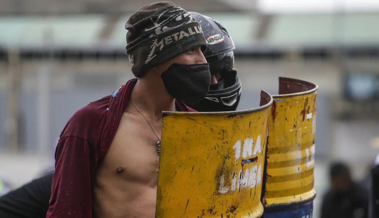 Pengunjuk rasa anti-pemerintah berdiri dengan perisai mereka selama kebuntuan dengan polisi di Madrid, di pinggiran Bogota, Kolombia (28/5/2021). Warga Kolombia telah turun ke jalan selama berminggu-minggu setelah pemerintah mengusulkan kenaikan pajak. (AP Photo/Ivan Valencia)