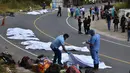 Tim forensik menutupi tubuh penumpang yang tewas dalam kecelakaan bus yang menabrak truk trailer di Gualan, Guatemala (21/12/2019). Kecelakaan tersebut menewaskan sedikitnya 21 orang dan menyebabkan belasan orang luka-luka. (AP Photo/Carlos Cruz)