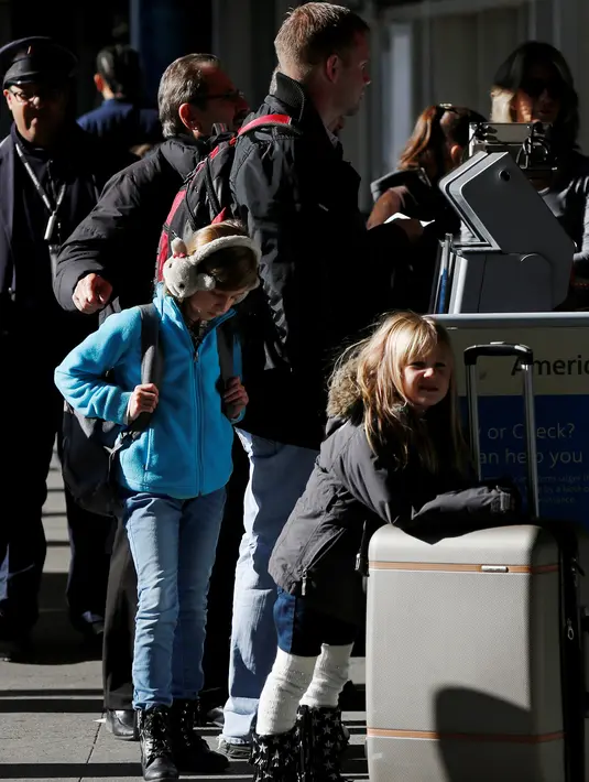 Dua orang bocah ikut mengantre bersama orang tuanya di Bandara LaGuardia, New York, Rabu (23/11). Di Amerika Serikat, tradisi mudik dilakukan saat hari perayaan Thanksgiving yang jatuh setiap Kamis keempat di November. (REUTERS/Shannon Stapleton)