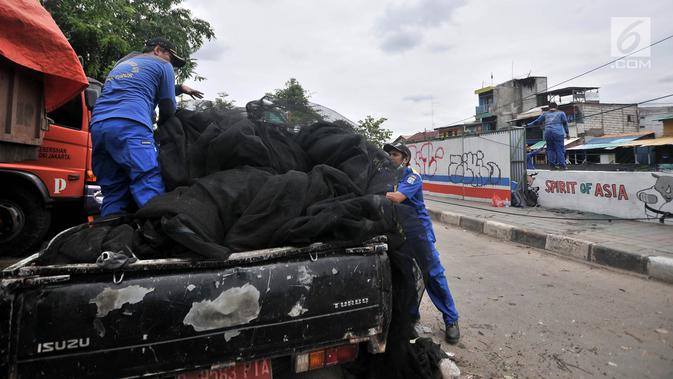 Petugas menata kain waring atau jaring ke atas mobil yang sebelumnya menutupi Kali Item di Kemayoran, Jakarta, Rabu (14/11). Pelepasan waring tersebut dilakukan lantaran banyak warga yang membuang sampah di atasnya (Merdeka.com/Iqbal S. Nugroho)
