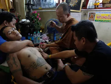 Seorang biksu Budha saat menato seorang pria menggunakan jarum tradisional di Wat Bang Phra, Nakhon Pathom, Thailand , (18/3). Setiap tahun saat musim semi, ribuan orang datang ketempat ini untuk menato tubuhnya. (REUTERS / Chaiwat Subprasom)