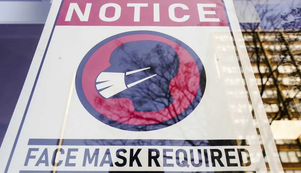 Sebuah tanda yang mewajibkan masker dipasang di depan toko di Philadelphia, Rabu (16/2/2022). Pejabat kota Philadelphia mencabut mandat vaksin untuk makan di dalam ruangan dan tempat lain yang menyajikan makanan dan minuman, tetapi mandat masker dalam ruangan tetap berlaku. (AP Photo/Matt Rourke)