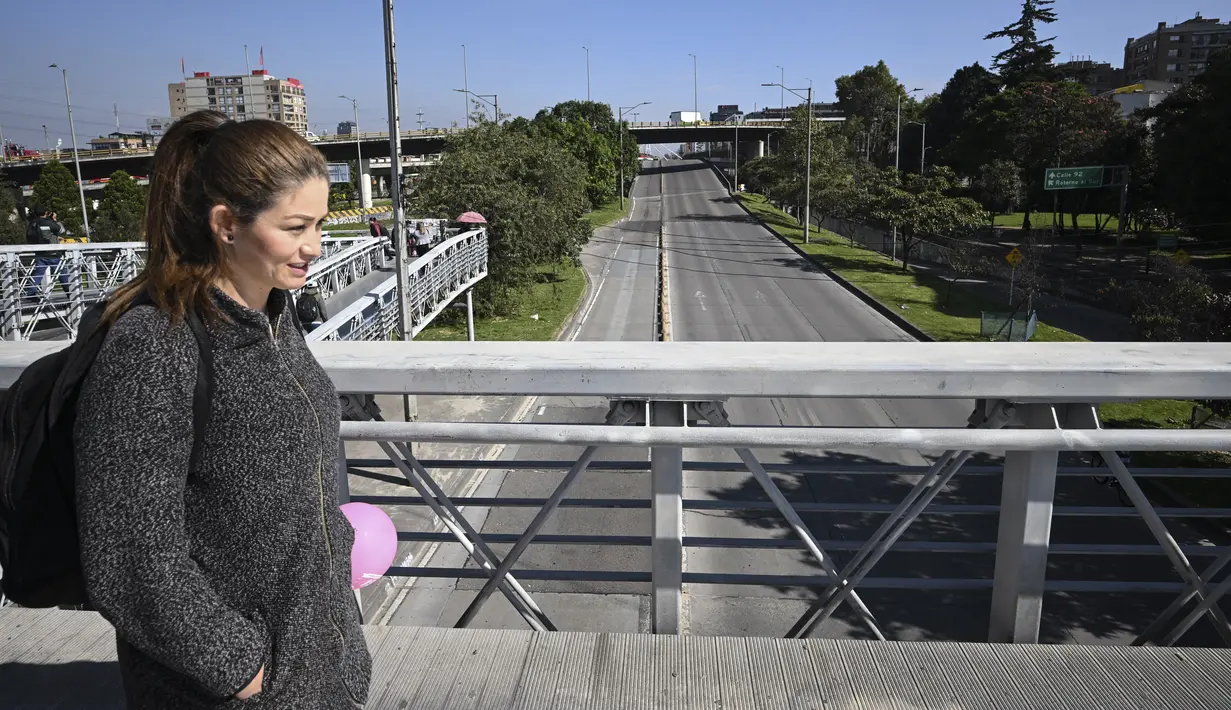 Seorang perempuan melintasi jembatan di atas jalan raya utama selama Car Free Day -hanya bus dan taksi yang diizinkan- di Bogota pada 2 Februari 2023. Kantor Wali Kota Bogota mengatakan acara ini berfungsi untuk "memiliki polusi (CO2) 57% lebih sedikit di lingkungan kita" karena hampir dua juta mobil pribadi dan setengah juta sepeda motor berhenti beredar. (Juan BARRETO / AFP)