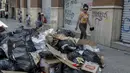 Seorang wanita berjalan melewati tumpukan sampah akibat pemogokan petugas sampah di Santiago (14/11/2019). Protes kekerasan meletus di ibukota Chile, Santiago, pada Selasa ketika mata uang negara itu turun ke level terendah dalam sejarah. (AFP/Javier Torres)