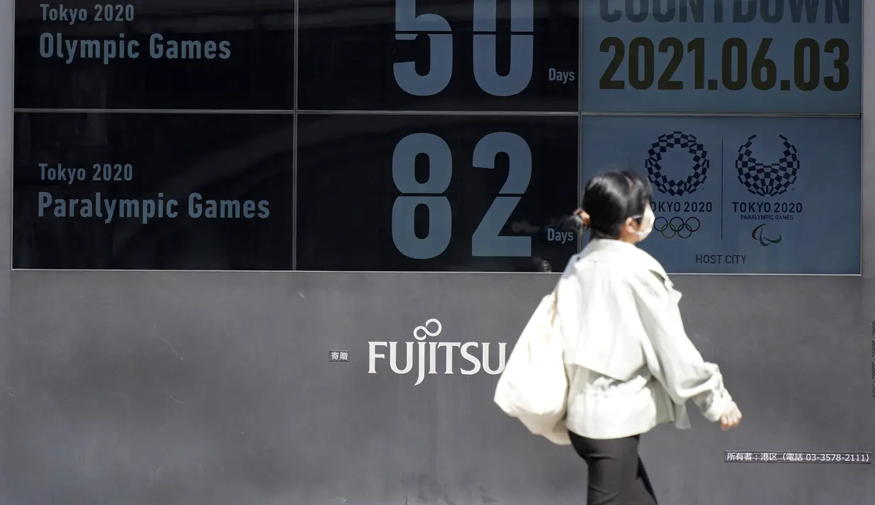 Seorang wanita berjalan di dekat jam hitung mundur untuk Olimpiade dan Paralimpiade Tokyo 2020 di dekat stasiun Shimbashi untuk menandai 50 hari sebelum dimulainya Olimpiade Musim Pana di Tokyo, Kamis (3/6/2021). (AP Photo/Kntaro Komiya)