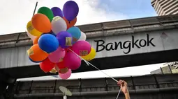 Seorang pengunjuk rasa memegang balon dengan pesan anti-pemerintah selama demonstrasi menentang usulan pembelian kapal selam oleh pemerintah yang berpihak pada militer di Bangkok (31/8/2020). (AFP/Lillian Suwanrumpha)