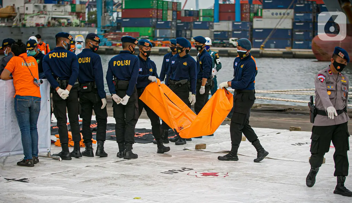 Petugas membawa body part dari kapal Basarnas di JICT II Tanjung Priok, Jakarta, Jumat (15/1/2021).  Badan SAR Nasional (Basarnas) kembali menerima paket kiriman hasil pencarian hari ketujuh. (Liputan.com/Faizal Fanani)