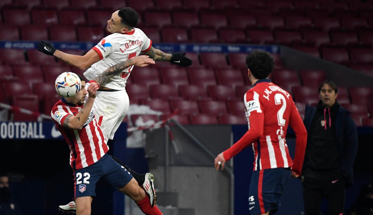 Pemain Atletico Madrid, Mario Hermoso, duel udara dengan pemain Sevilla, Lucas Ocampos, pada laga Liga Spanyol di Stadion Wanda Metropolitano, Selasa (12/1/2021). Atletico Madrid menang dengan skor 2-0. (AFP/Pierre-Philippe Marcou)