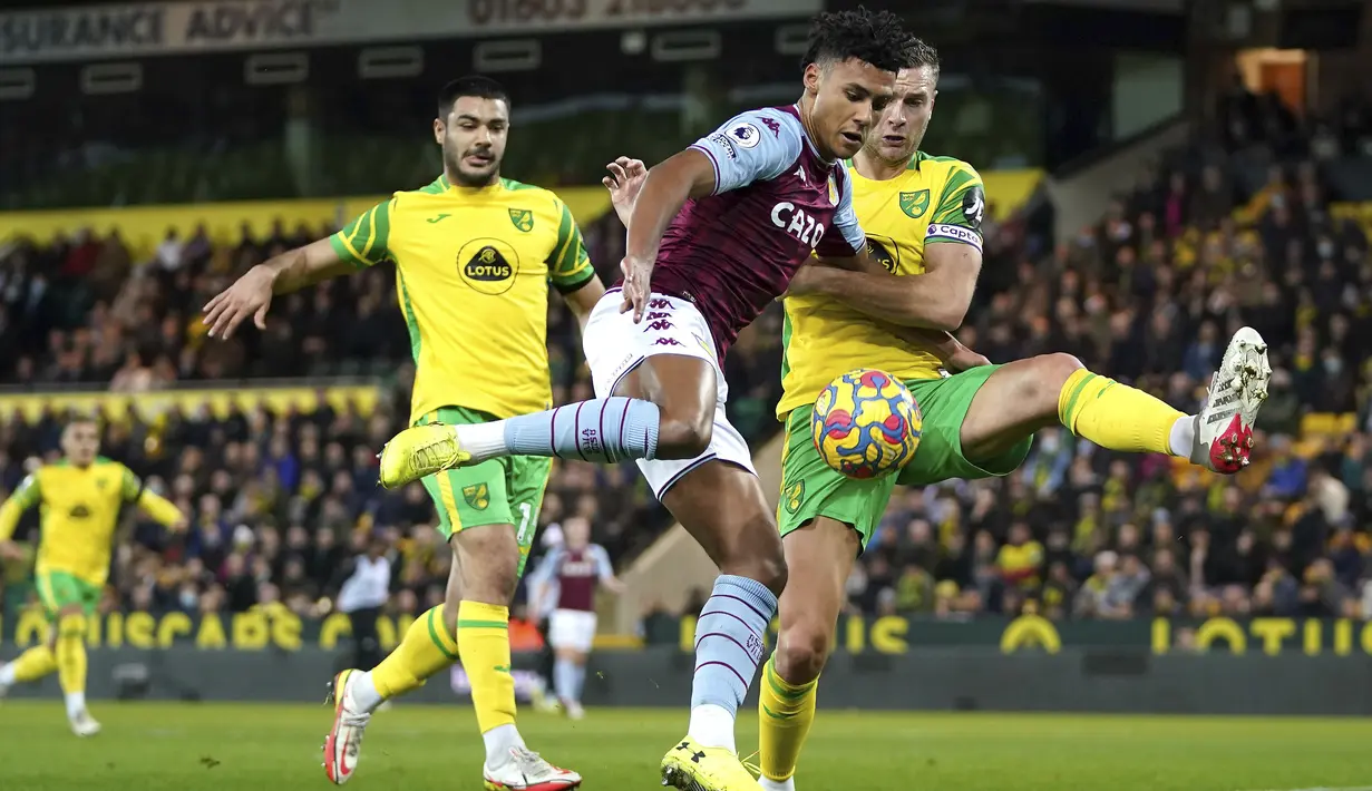 Penyerang Aston Villa Ollie Watkins berebut bola dengan bek Norwich City Ben Gibson dalam lanjutan Liga Inggris di Carrow Road, Rabu (15/12/2021) dini hari WIB. Aston Villa sukses menekuk tuan rumah Norwich City 2-0. (Joe Giddens/PA via AP)