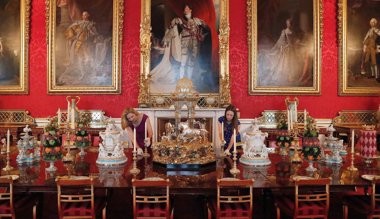 Pekerja menata meja makan yang digunakan semasa pemerintahan Ratu Victoria sebagai bagian dari pameran di Istana Buckingham, London, Rabu (17/7/2019). Pameran yang dibuka pada 20 Juli tersebut menandai peringatan 200 tahun kelahiran Ratu Victoria. (AP Photo/Frank Augstein)